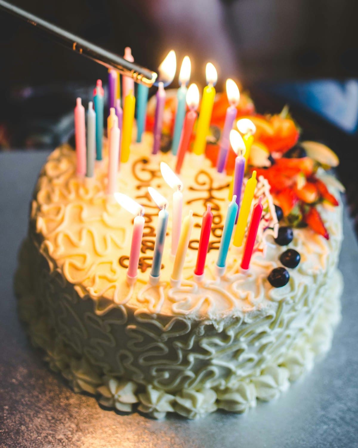 A hand lighting the candles on a birthday cake