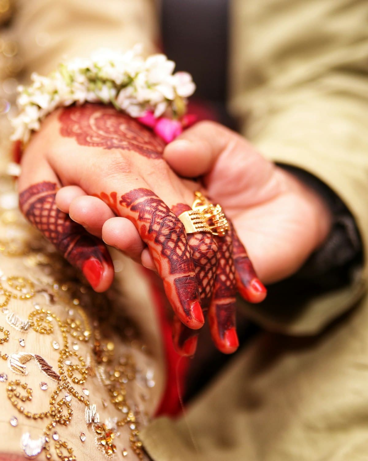 Two hands joined, one wearing a gold band