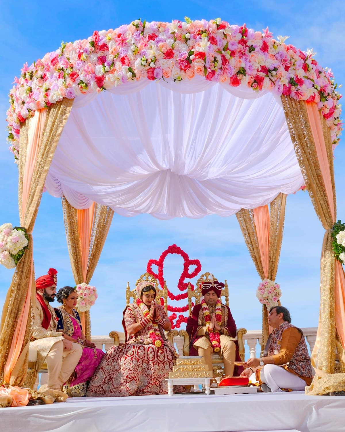 A couple seated beneath a floral canopy during a wedding ceremony